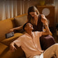 A couple enjoying music together on a sofa, illustrating the long battery life of the Bose SoundLink Home Speaker which provides up to 9 hours of playtime from morning to night.
