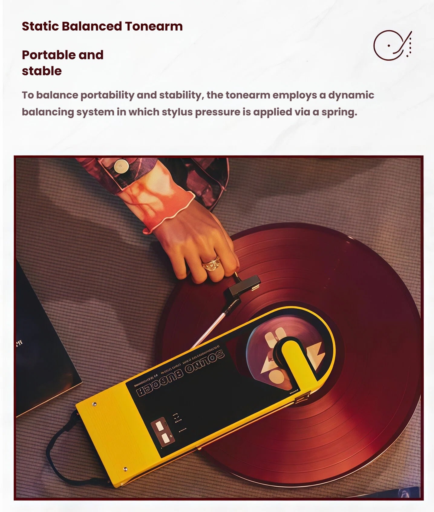 Hand placing yellow Audio-Technica Sound Burger on red vinyl, demonstrating spring-balanced tonearm for stable playback.