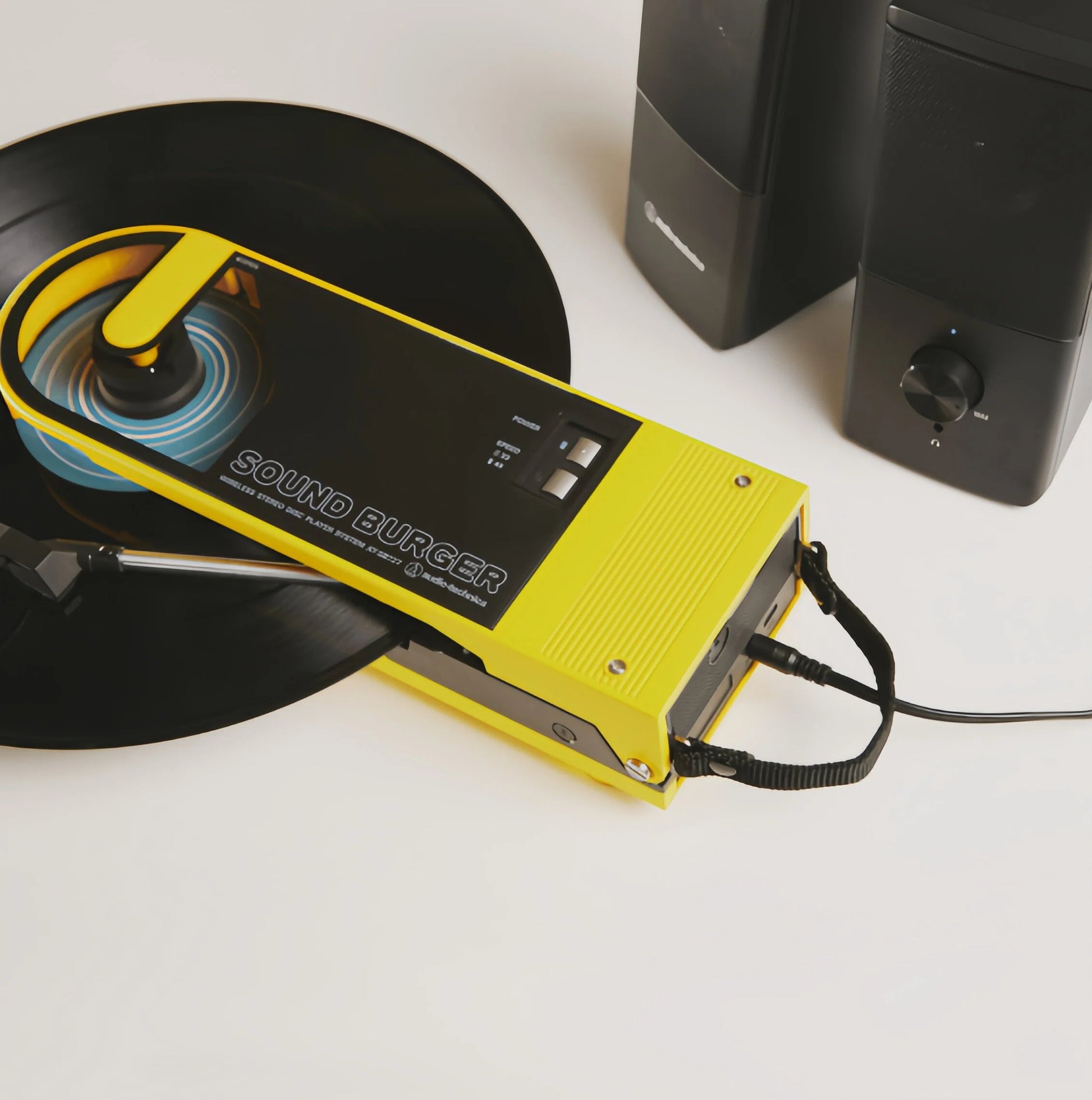 Yellow Audio-Technica Sound Burger connected via cable to external speakers, demonstrating wired audio output.