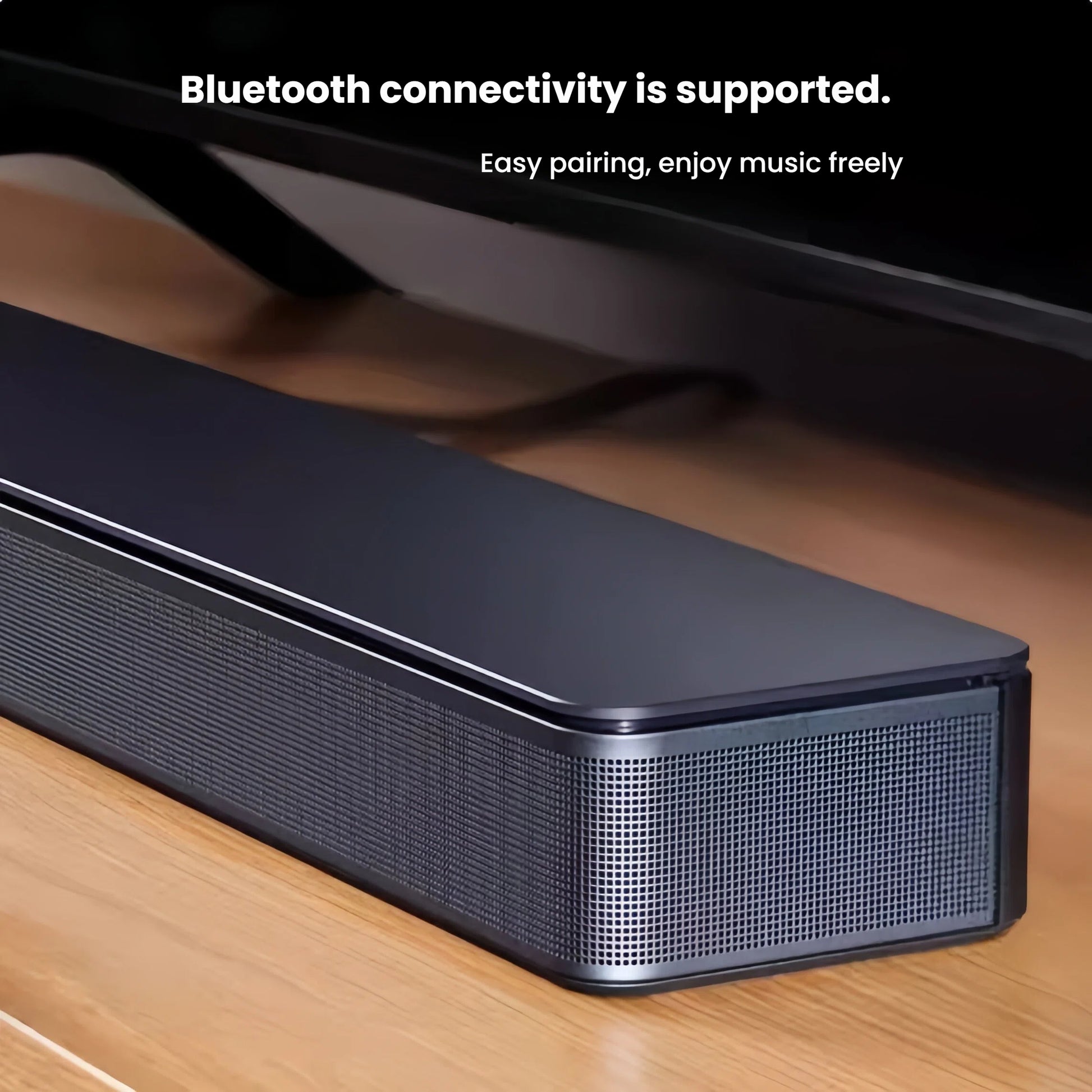 A close-up angle of the Bose TV Speaker on a wooden surface, highlighting its premium grille and build quality, with text emphasizing its easy Bluetooth pairing for wireless music.