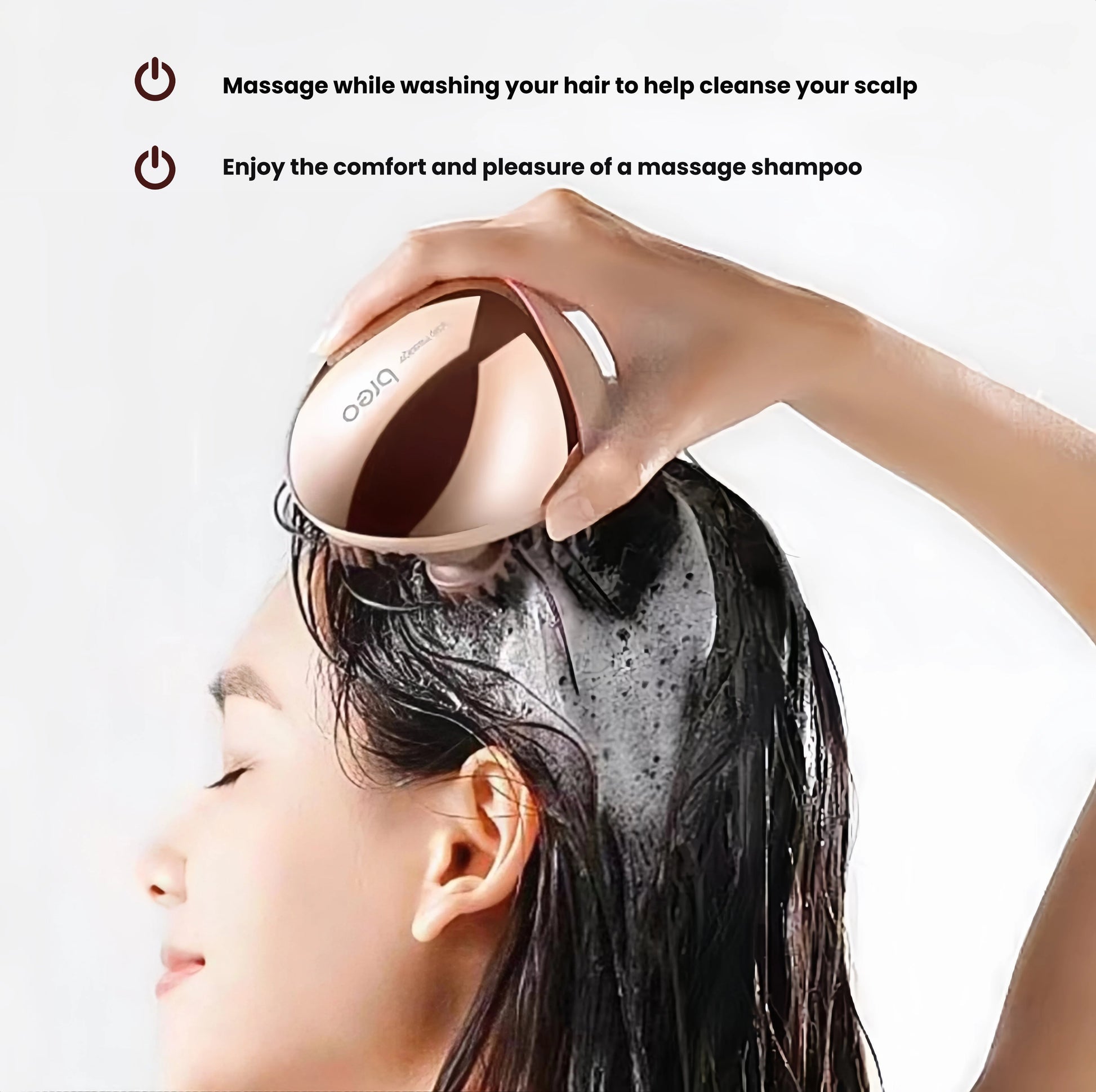 A person using the Breo Scalp Mini while washing their hair in the shower. The IPX7 waterproof design allows safe use with shampoo to cleanse and stimulate the scalp effectively.