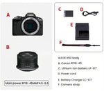 Flat-lay of Canon EOS R50 kit: black body, RF-S 18-45 mm lens, LP-E17 battery, charger, strap, and power cord.