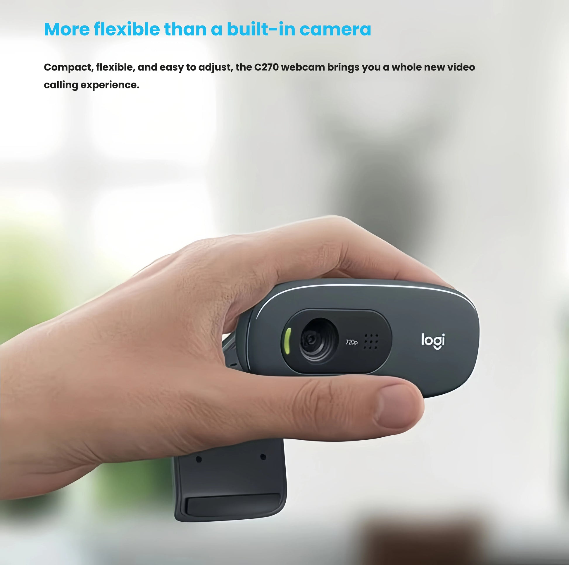 Hand holding the small Logitech C270 webcam, demonstrating its portable, adjustable design for laptops, monitors, or tripods.