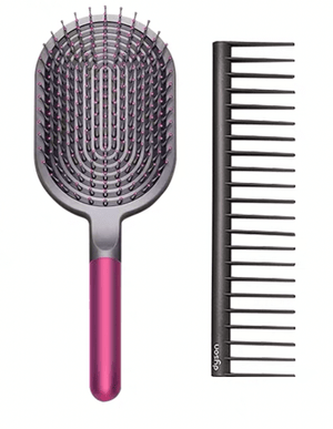 Image of a hair care set featuring a wide paddle brush with a curved design and pink handle, alongside a black wide-tooth comb. The brush has a flexible, ventilated structure with rounded bristles for gentle detangling, while the comb, labeled with the 'Dyson' logo, is designed for precise styling and easy detangling of wet or dry hair.