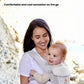 Mother carrying baby in Ergobaby Omni Classic Mesh Carrier at beach—lightweight, breathable mesh fabric provides cool, comfortable sensation during outdoor activities.