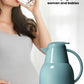 A pregnant woman drinking a glass of water with the blue FEENIK insulated jug in the foreground, emphasizing its food-grade, healthy materials that are safe for the whole family.