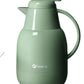 A front view of the FEENIK 1-liter thermal coffee and tea carafe in a modern sage green finish, featuring an ergonomic handle and a push-button lid for easy pouring.
