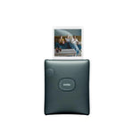 Fujifilm Instax Square Link smartphone printer in dark green with a printed square photo emerging. Features textured design, dedicated power button, and sleek compact build for portable instant printing.