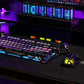 The GravaStar Mercury K1 Lite mechanical keyboard displayed on a premium gaming desk setup with matching RGB mouse and neon clock. The keyboard’s glowing blue and purple lights sync with the ambient lighting, creating a cohesive, high-tech gaming environment ideal for streamers and gamers.