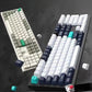 Side-by-side display of two Keychron Q6 Max keyboards in contrasting color schemes: one with white and olive green keycaps, the other with black and teal accents, highlighting premium build quality and customizable aesthetics.
