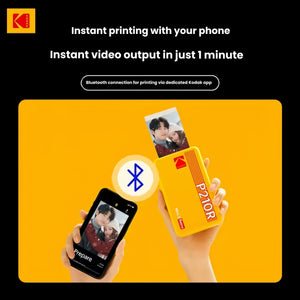 Hands holding Kodak Mini 2 Retro printer (yellow) and smartphone connected via Bluetooth. Shows instant photo printing from phone using dedicated Kodak app. Perfect for quick, wireless photo output.