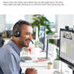 Smiling professional wearing the black Logitech H390 headset during a video conference on a desktop monitor, showcasing the 233 cm cable and noise-canceling microphone.