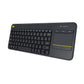 3/4-angle view of the Logitech K400 Plus showing the slim profile and built-in touchpad with yellow accent line, ideal for couch or living-room use.