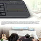 Close-up of the K400 Plus’s large touchpad and media keys, overlaid on an illustration of a modern living room, emphasizing seamless control of a PC-TV entertainment system.