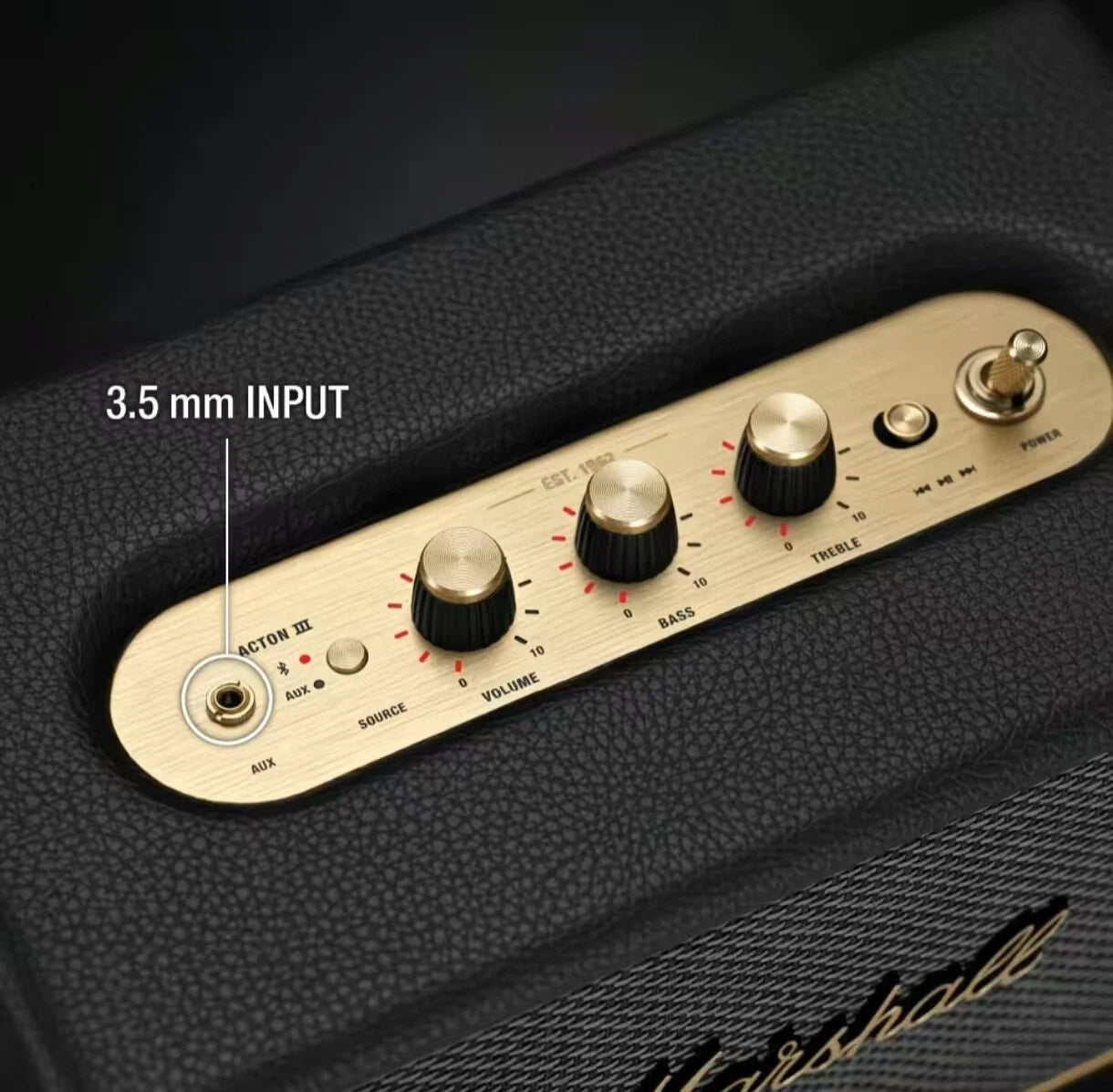  Close-up of the Marshall Stanmore III’s brass-finished control panel featuring 3.5 mm aux input, volume, bass, and treble knobs for precise sound tuning.