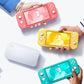 Overhead shot of three people holding coral, yellow and turquoise Nintendo Switch Lite consoles next to a white carrying case, showcasing the compact, portable design.