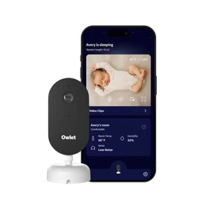 Owlet Dream Sight baby monitor camera next to smartphone app showing live feed of sleeping baby, room temperature (68°F), humidity (32%), low noise level, and video clips