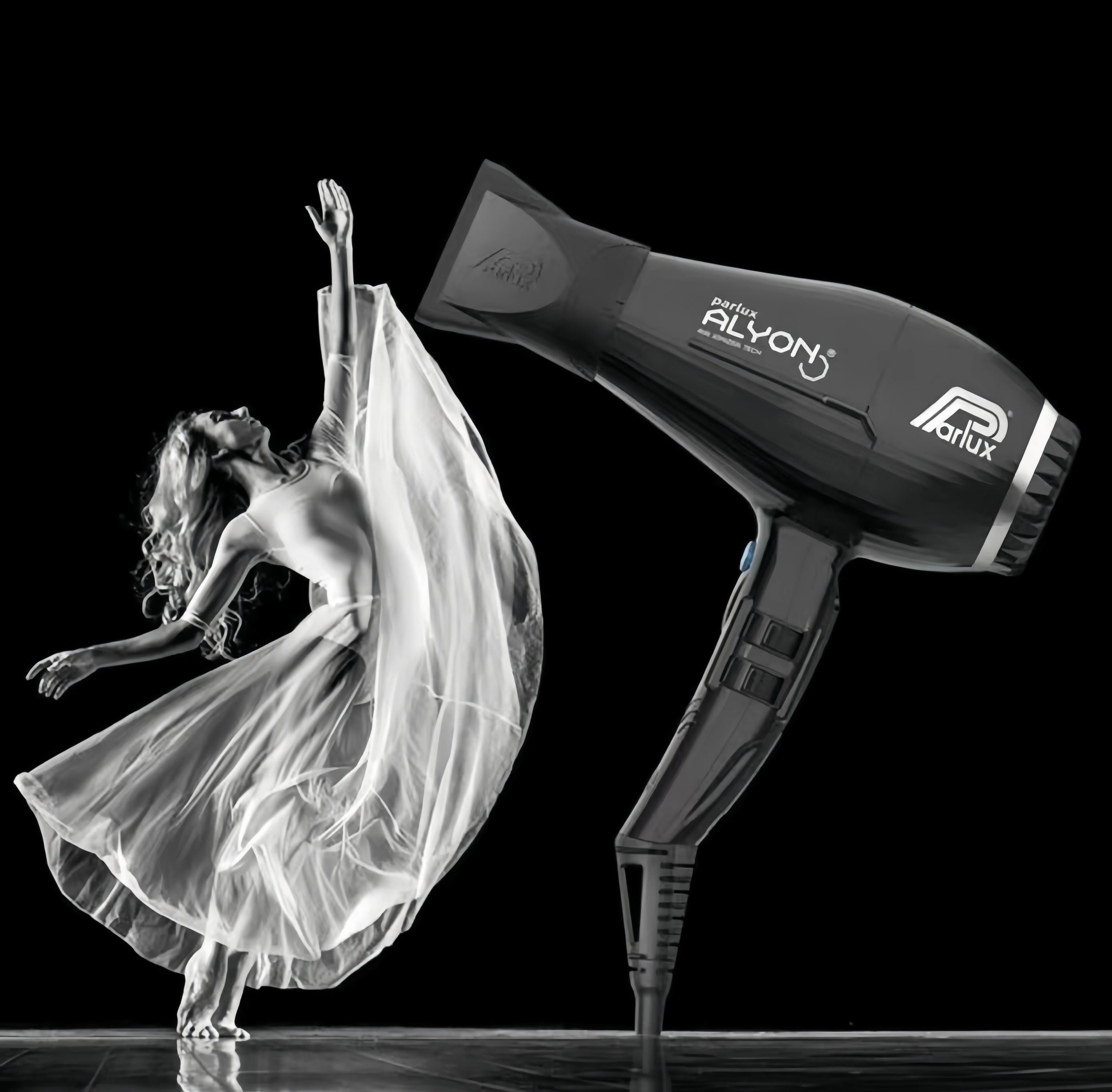 Artistic black and white image of a dancer in flowing dress next to a Parlux Alyon hair dryer, symbolizing powerful airflow and graceful hair movement.