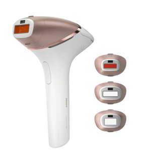 Image of a handheld IPL (Intense Pulsed Light) hair removal device in a sleek white and rose gold design. The device comes with three interchangeable attachment heads for different body areas, each designed with specialized treatment windows. The attachments are color-coded for easy identification and suited for face, body, and precision areas