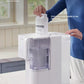  A person easily replacing the Aquaporin composite filter cartridge in the white Philips desktop drinking water machine using the simple QuickTwist technology, no technician required.