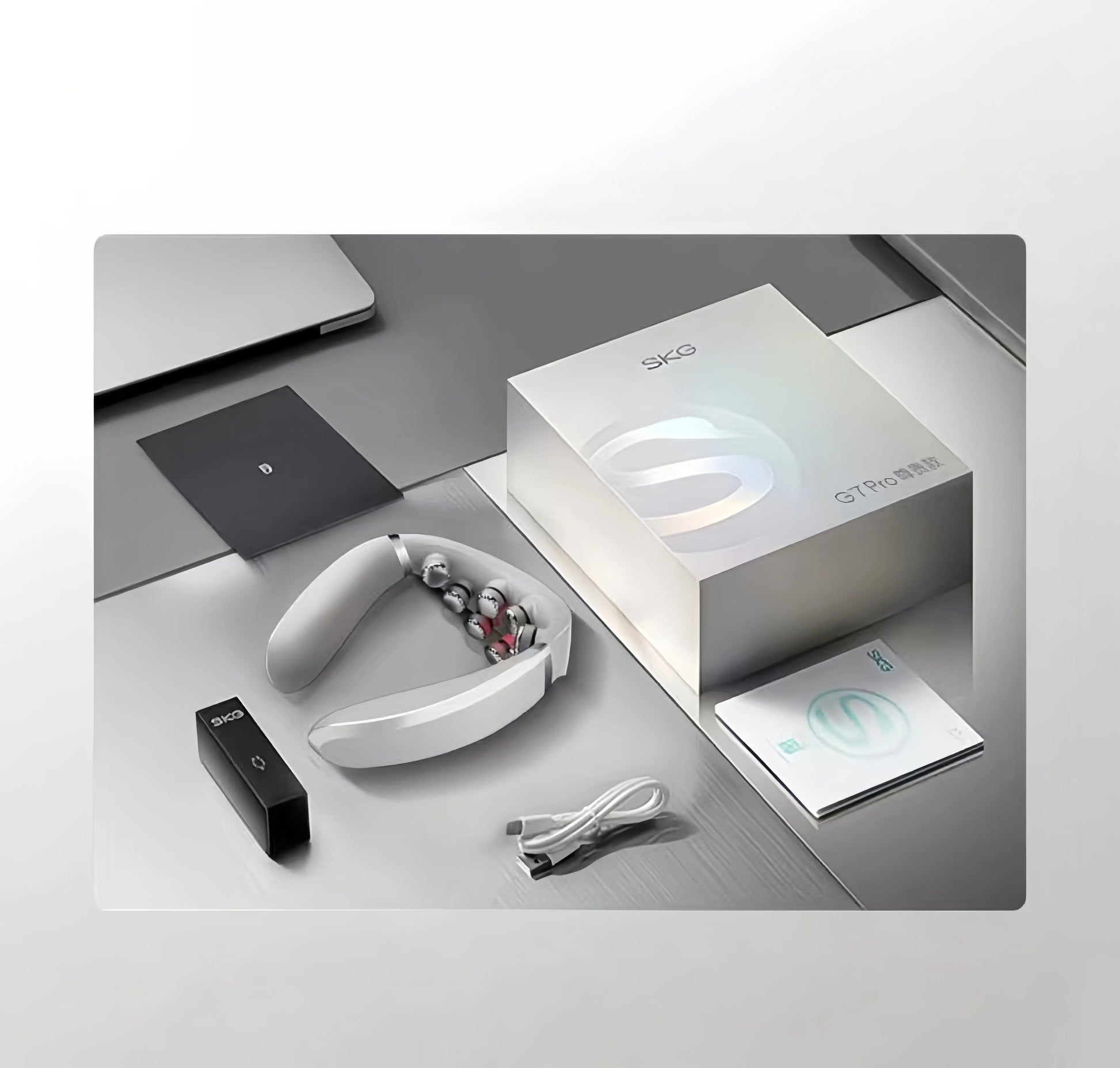 Unboxing view of SKG G7 Pro foldable neck massager featuring sleek white device, compact remote control, USB-C charging cable, user manual, and premium SKG-branded box on a modern desk setup.