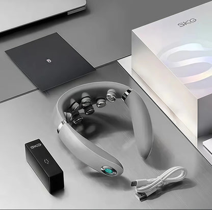 Front-facing product shot of SKG G7 Pro foldable neck massager in silver-gray finish, displayed with black remote control and USB-C cable on a minimalist workspace, highlighting its premium build and smart functionality.