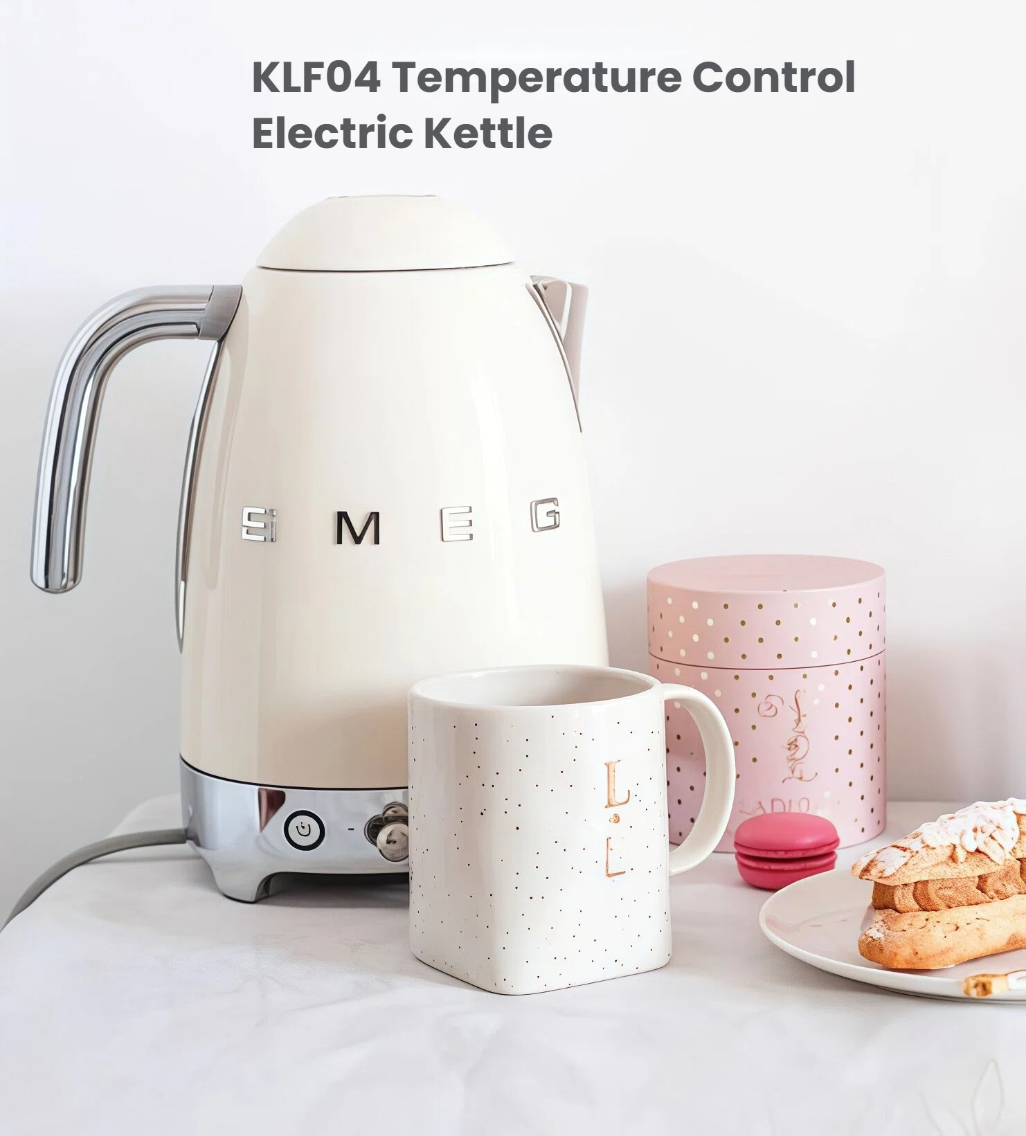 The Smeg KLF04 50's Style Temperature Control Electric Kettle in a cream finish, displayed next to a mug and pastry to showcase its elegant retro design for any stylish kitchen.