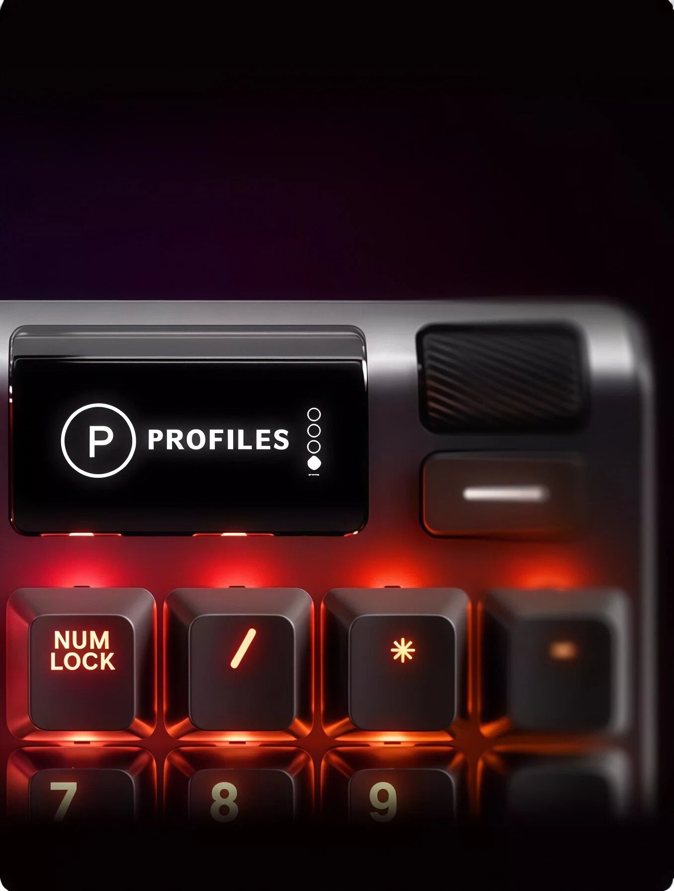Close-up of the SteelSeries Apex 5’s onboard OLED display showing “Profiles” with four preset options, located above the numeric keypad. Features illuminated Num Lock key and customizable lighting controls for advanced gaming profiles.