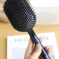 Image of a hair care set featuring a wide paddle brush with a curved design and pink handle, alongside a black wide-tooth comb. The brush has a flexible, ventilated structure with rounded bristles for gentle detangling, while the comb, labeled with the 'Dyson' logo, is designed for precise styling and easy detangling of wet or dry hair.
