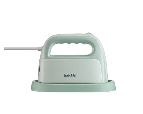 The Keheal portable handheld garment steamer in a light mint green color, shown from the side while resting on its protective heat-resistant base.