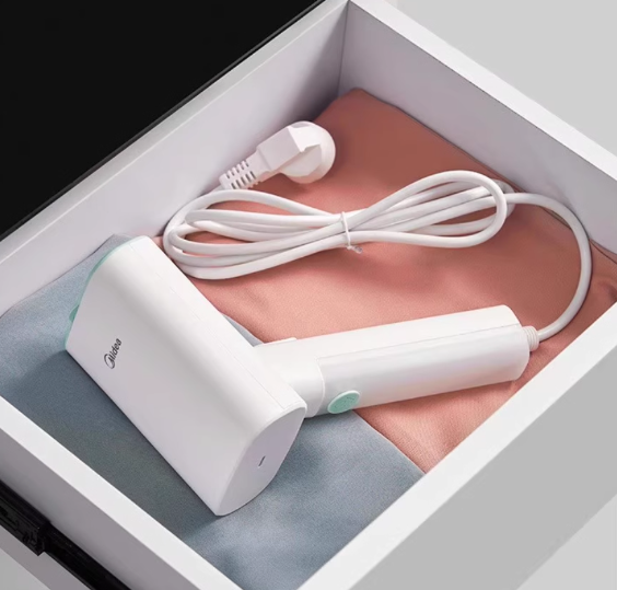 The compact Midea portable travel steamer shown stored neatly inside a drawer, highlighting its space-saving design perfect for home and travel.