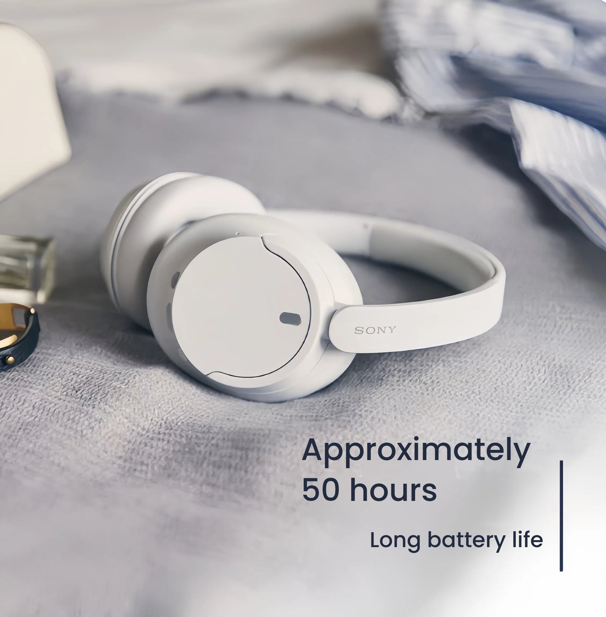  The white Sony WH-CH720N wireless headphones resting on a bed, highlighting their long battery life of approximately 50 hours.